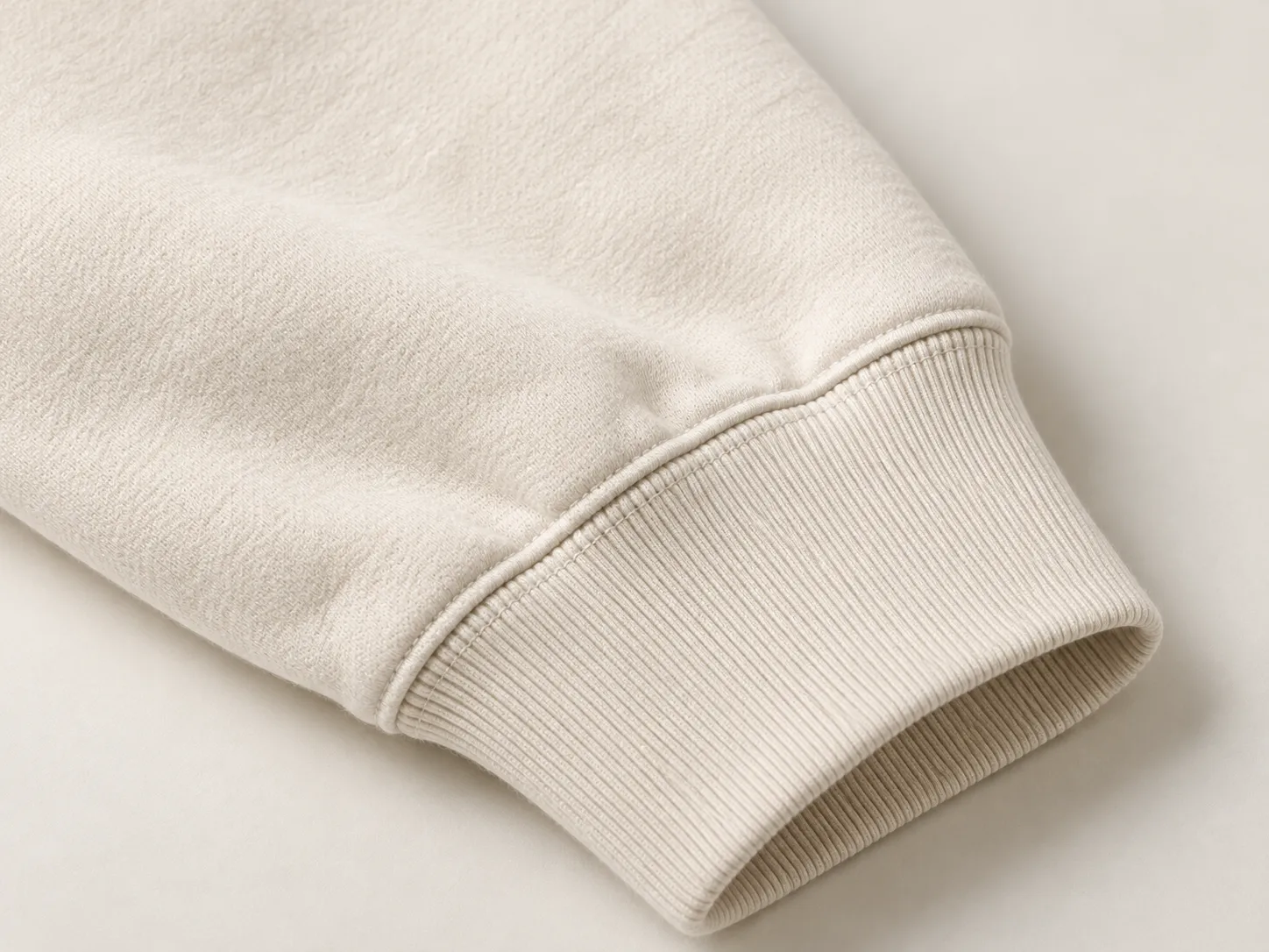 Close view of a light-colored sleeve seam and ribbed cuff