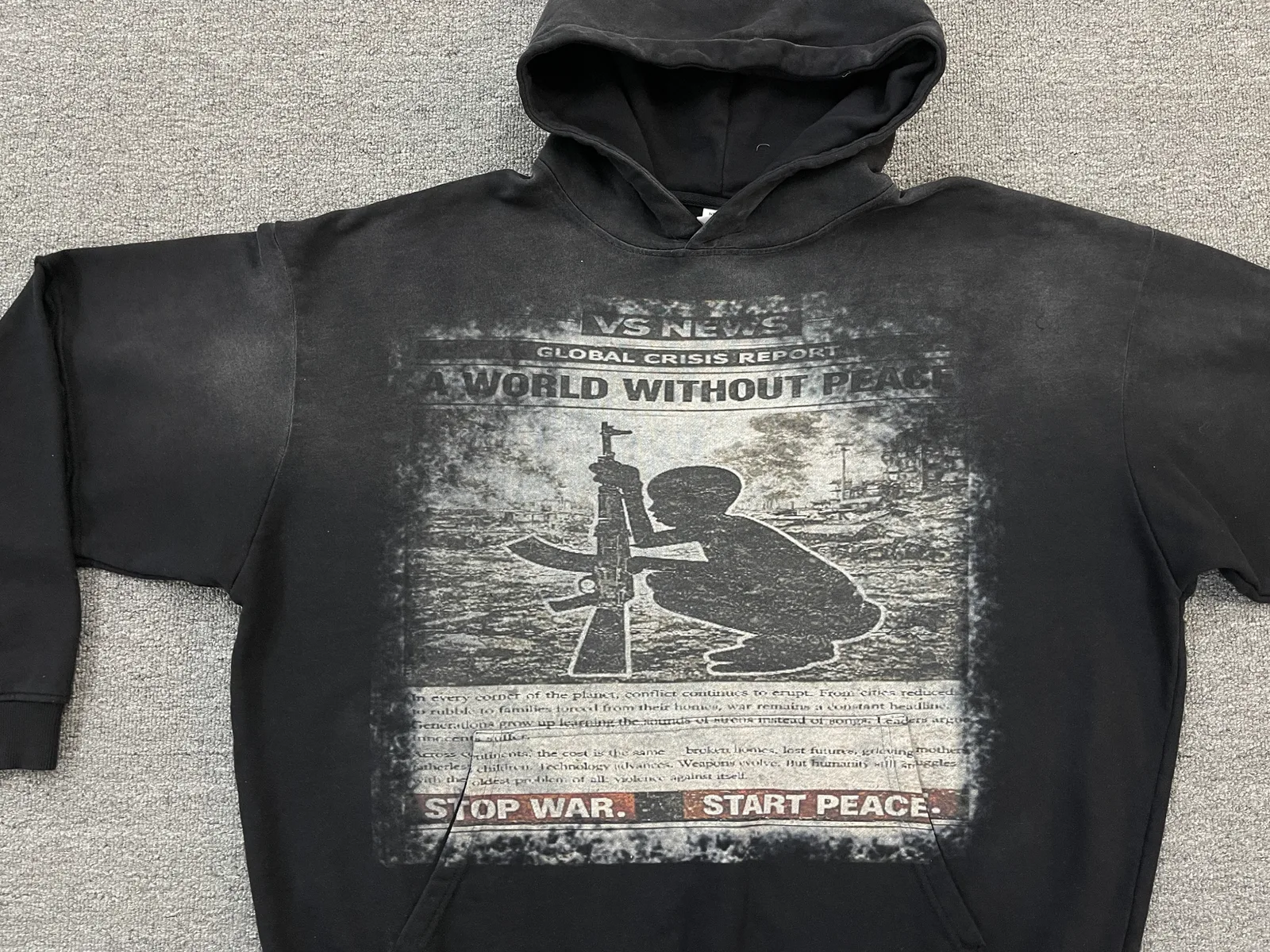 Black hoodie with a distressed monochrome newspaper-style graphic across the front.
