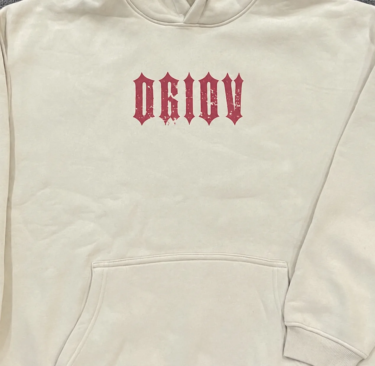 Red DRIOV lettering printed at the chest of a cream hoodie.