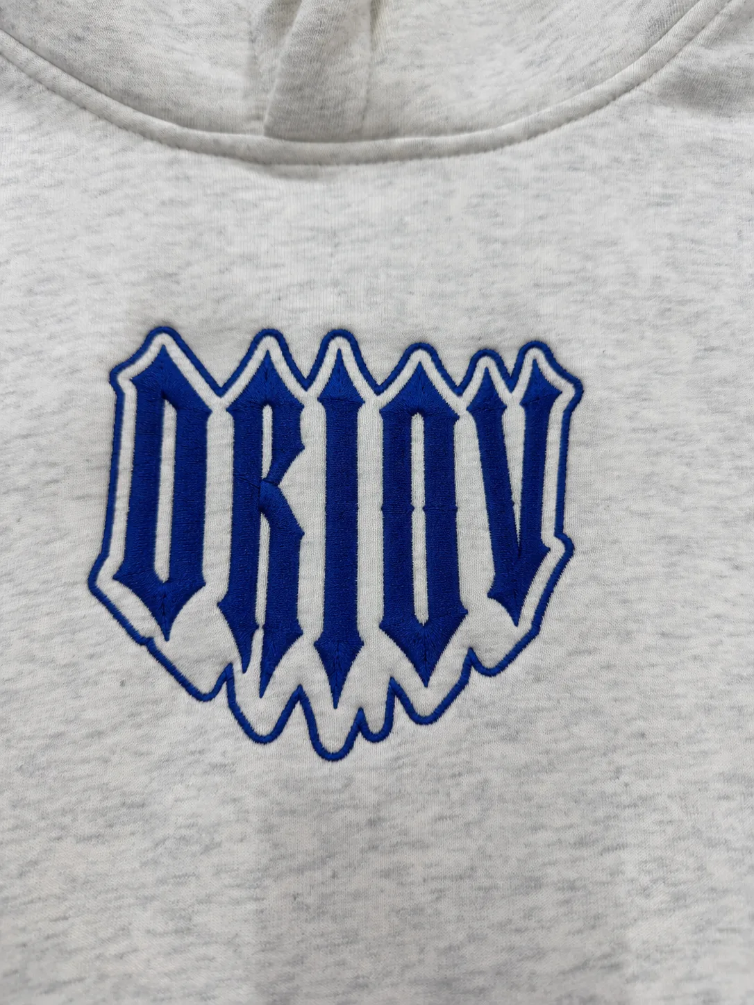 Blue outlined DRIOV embroidery on a grey sweatshirt.