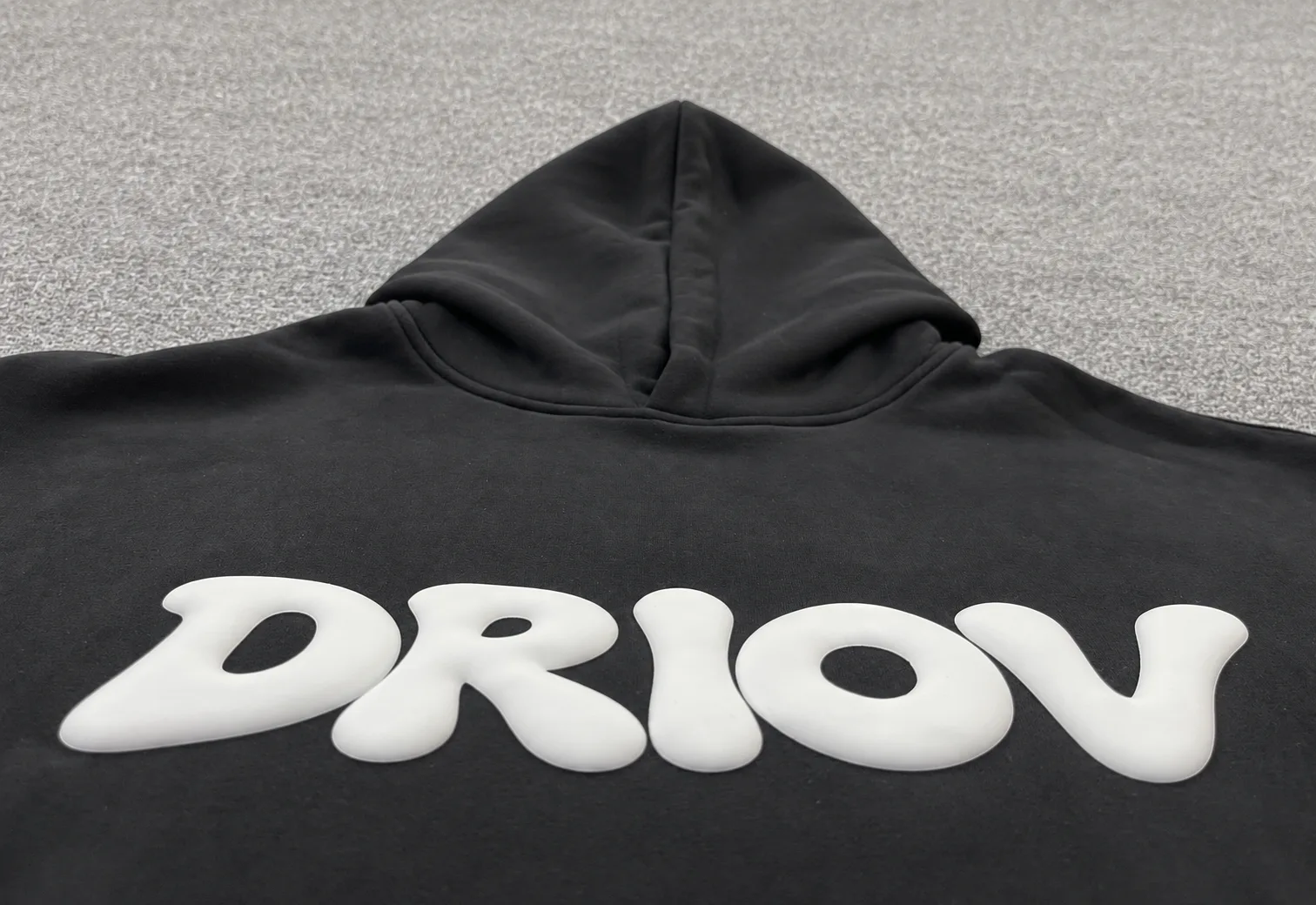 Raised white DRIOV lettering across the chest of a black hoodie.