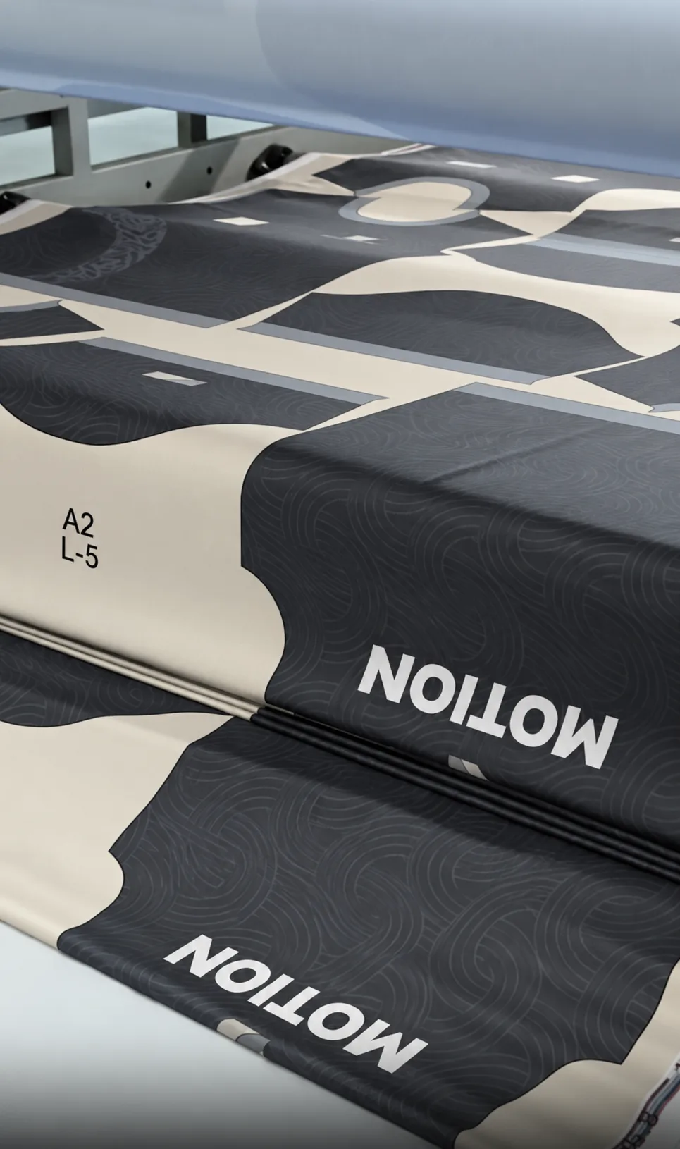 Black and light printed garment-panel shapes arranged on a roll-fed production surface.