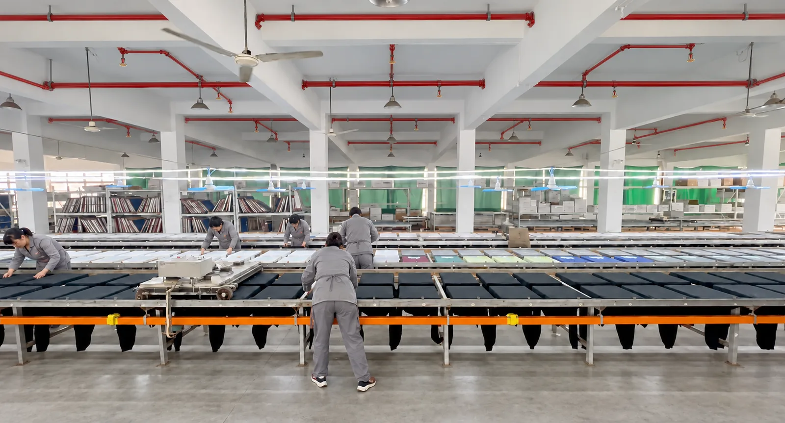 Staff working along garment-printing tables in the workshop.